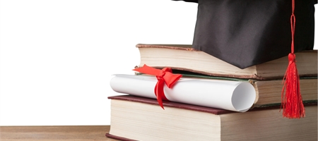 Graduation cap on top of books with a degree scroll