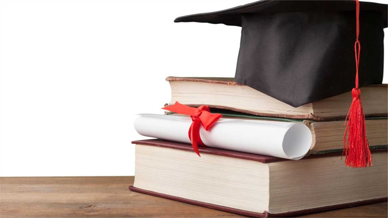 Graduation cap on top of books with a degree scroll