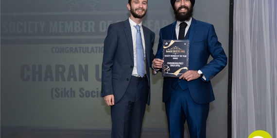 Two people holding the society member of the year award