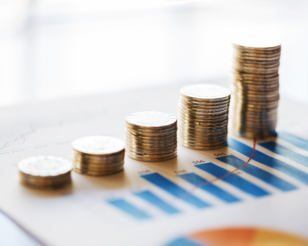 Five piles of coins mirroring the layout of a graph, piled on top of some financial documents