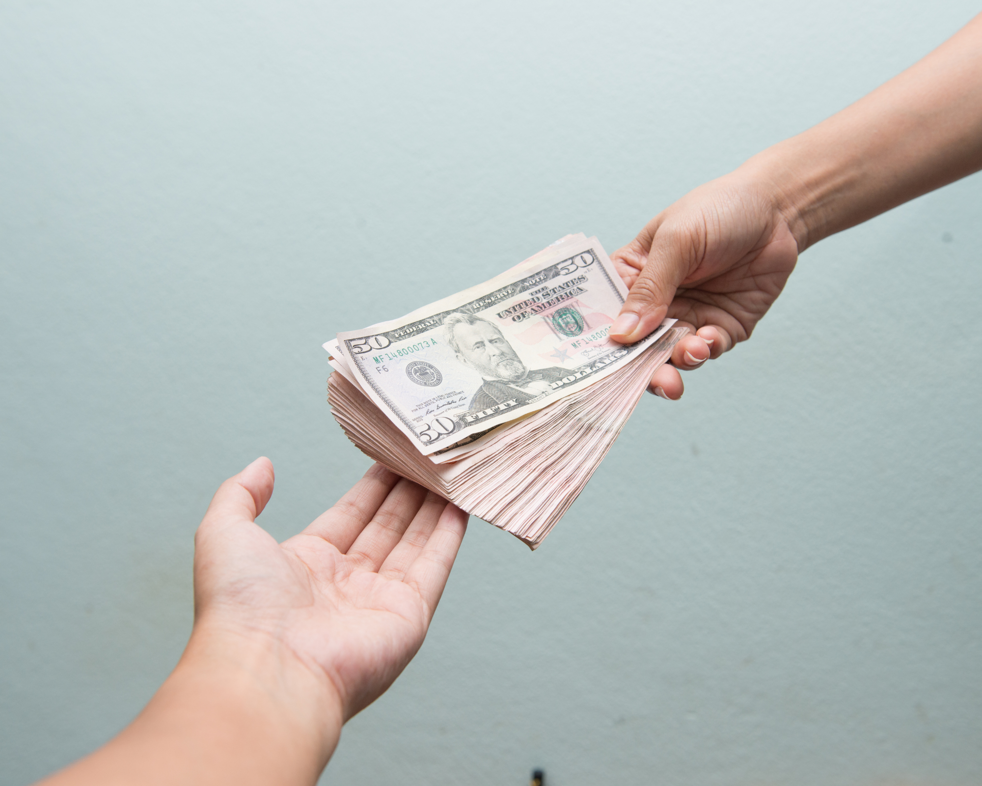 Image of a hand giving some money over to someone else