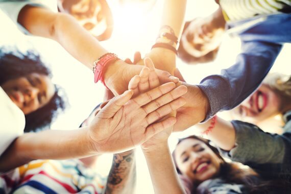 Students with their hands piled together in a circle.