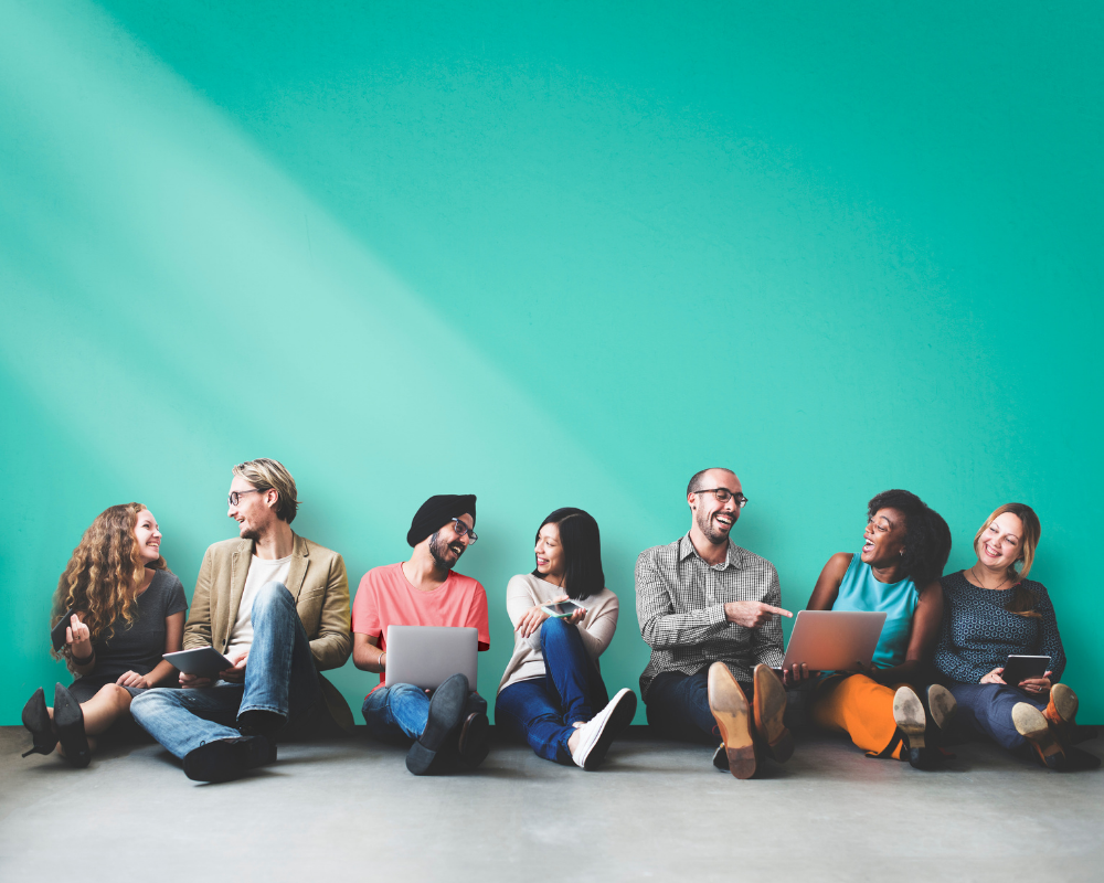 Image of a diverse group of friends sat against a wall chatting