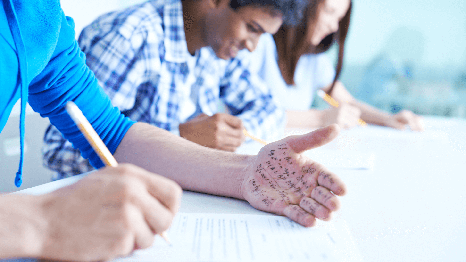 Student looking at hand with writing on it during exam