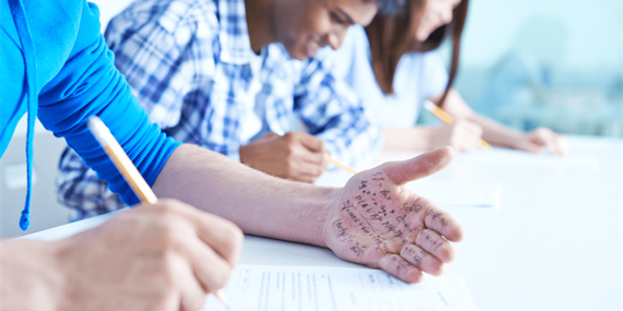 Student looking at hand with writing on it during exam