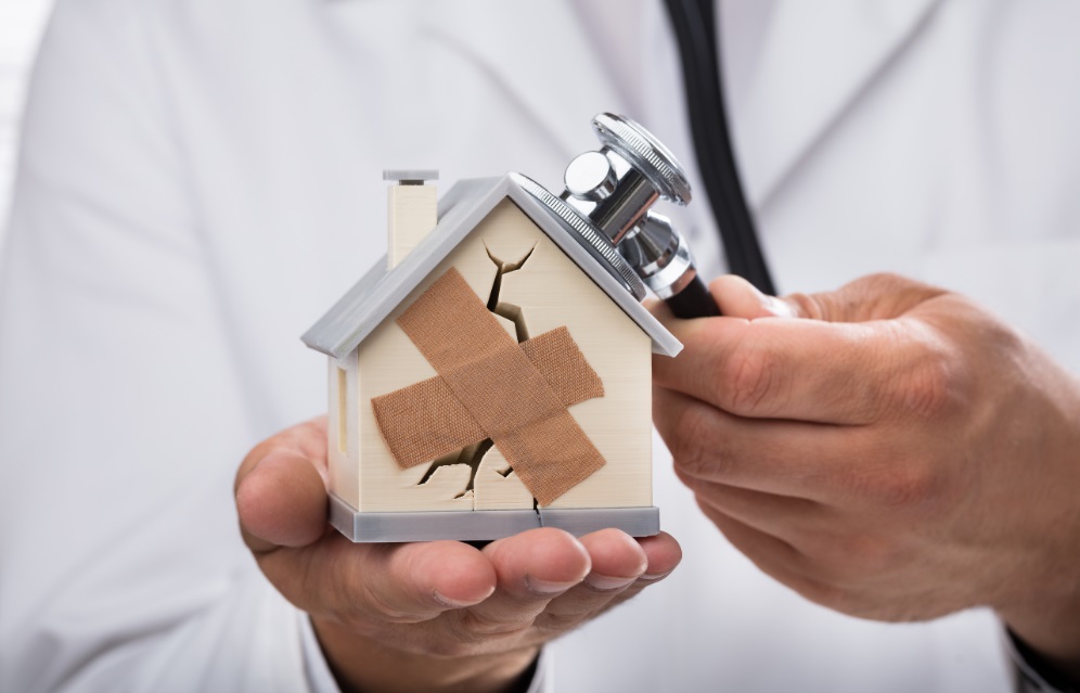 Doctor holding a small house with a plaster on it