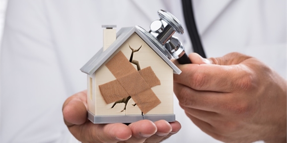 Doctor holding a small house with a plaster on it