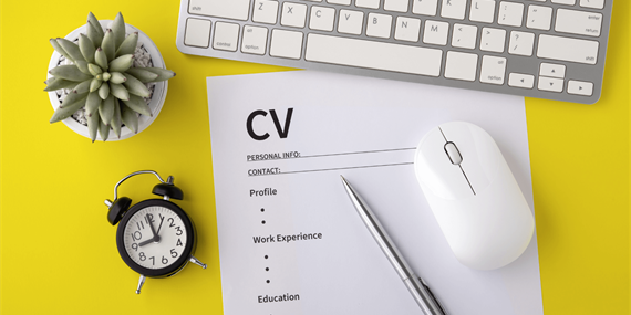 CV placed in front of a keyboard, with a pen, mouse and clock