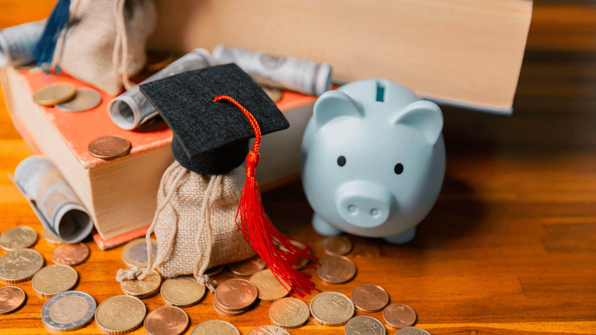 Piggy bank next to money, book and graduation cap