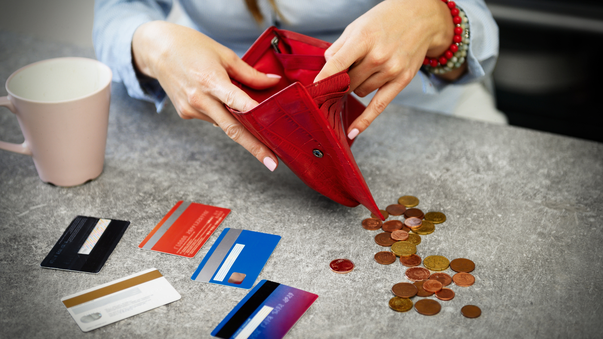 person looking into purse, with credit cards on table