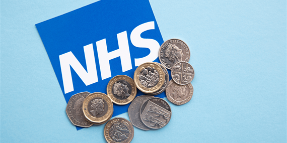 NHS sign partly covered by coins