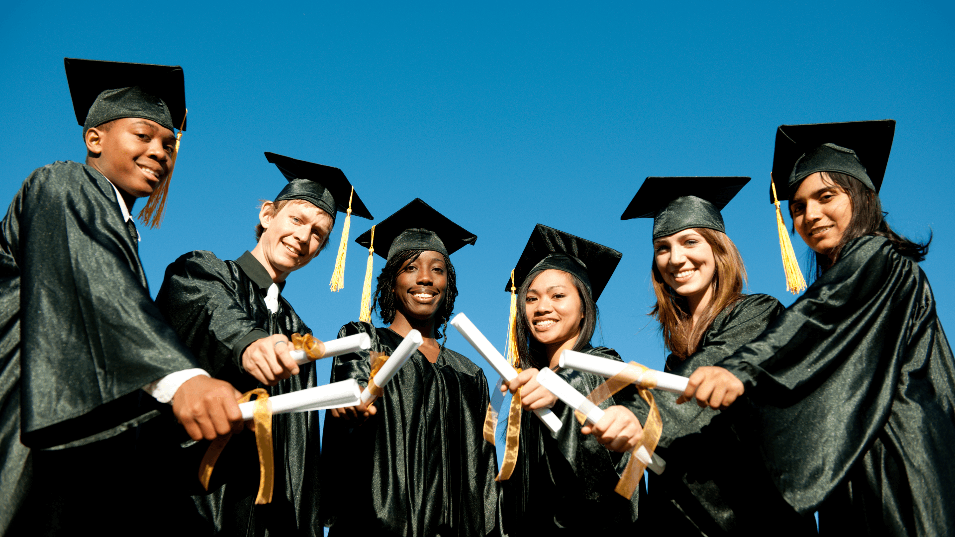 Graduates holding their diplomas to the camera