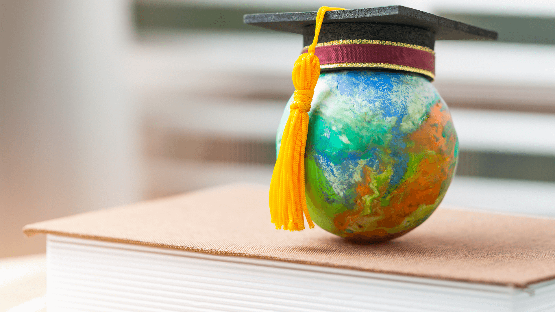 Globe wearing mortar board on top of a book